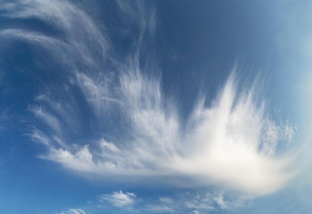 Luchtige wolken verscheurd door de wind in de blauwe lucht