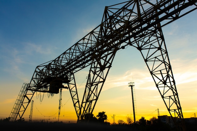 Luchtkraan bij het station. Kraansilhouet op zonsondergangachtergrond. Zware industrie concept.