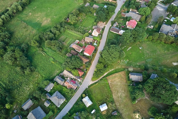 Luchtlandschapsmening van dorpshuizen en verre groene gecultiveerde landbouwgebieden met groeiende gewassen op heldere zomerdag