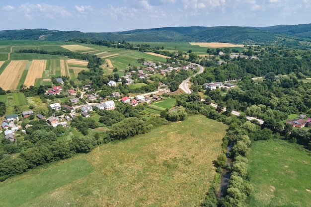 Luchtlandschapsmening van groene gecultiveerde landbouwgebieden met groeiende gewassen en verre dorpshuizen