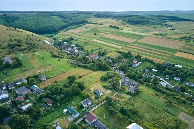 Luchtlandschapsmening van groene gecultiveerde landbouwgebieden met groeiende gewassen en verre dorpshuizen