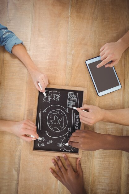 Luchtmening van bebouwde handen die bedrijfstermijnen op lei met persoon schrijven die digitale tablet gebruiken