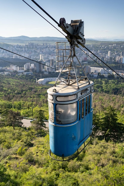 Luchtmening van de stad van Tbilisi van de oude blauwe kabelbaancabine van berg Georgië boven de stad