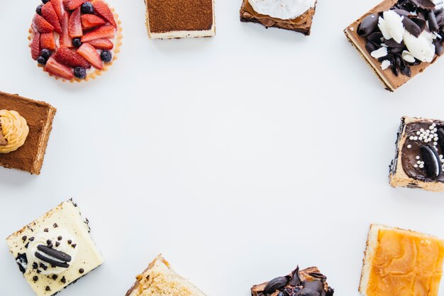 Luchtmening van heerlijke gebakjes die kader op witte achtergrond vormen