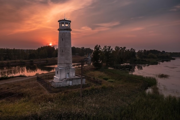 Luchtmening van oude vuurtoren op bank van kanaal tegen kleurrijke zonsonderganghemel dubna russia