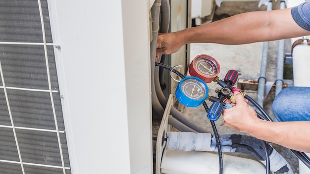 Luchtreparatiemonteur die meetapparatuur gebruikt voor het vullen van industriële fabrieksairconditioners.