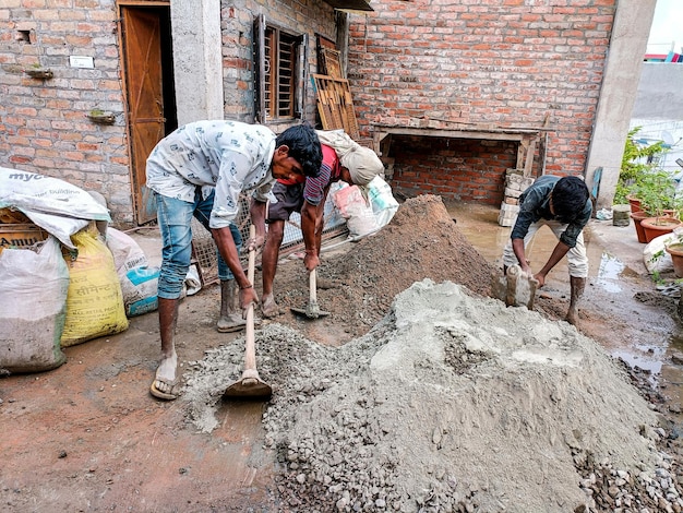 Lucknow, India, oktober 2021: Indiase arbeiders doen bouwwerkzaamheden handmatig op de vloer met behulp van een schop