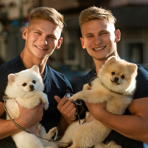 Photo lucky to be together twins men hold pedigree dogs happy twins with muscular look muscular men with dog pets spitz dogs love the company of their family happy family on walk