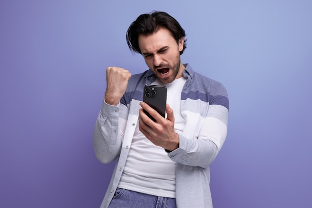 スマートフォンを手にしたカジュアルなスタイルの幸運なブルネットの男