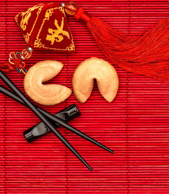 Lucky charm, fortune cookies and chopsticks. Chinese new year red background