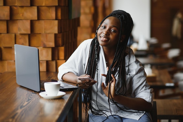 Lucky day. Emotional black woman looking at laptop, clenching fists and screaming, working at cafe, copy space