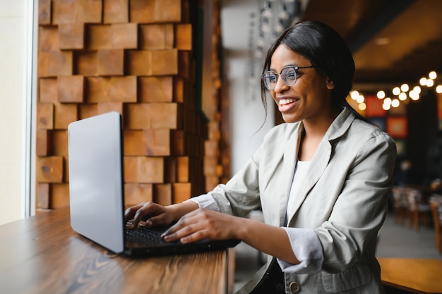 Lucky day Emotional black woman looking at laptop clenching fists and screaming working at cafe copy space