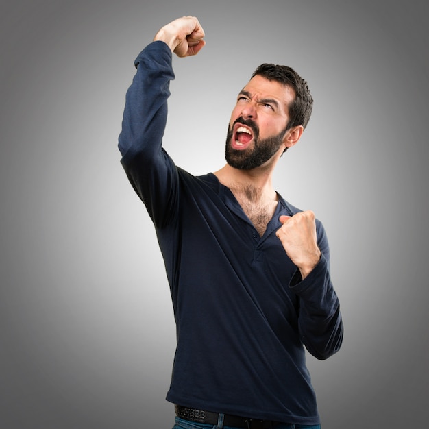 Lucky handsome man with beard on grey background