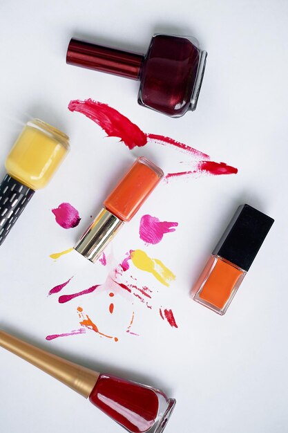 Lucky on a white background with smears of varnish Orange burgundy redChoosing varnishes for manicures in a beauty salon