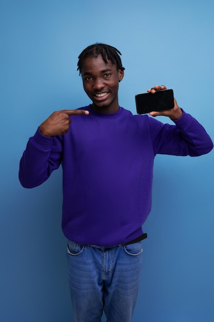 Счастливый победитель африканский молодой человек с дредами с телефоном на фоне студии