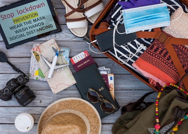 Bagagli pronti a viaggiare dopo il blocco, accessori femminili, portafogli passaporto per occhiali su fondo in legno - messaggio su tablet per evitare l'infezione da coronavirus