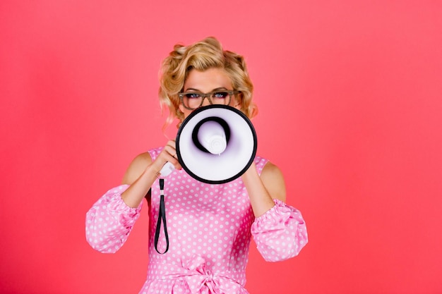 Luid spreken in de megafoon schoonheid vrouw met megafoon geïsoleerd op roze