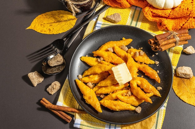 Luie pompoenbollen, gnocchi met boter en bruine suiker. Warm herfstgerecht, zoete gezonde voeding. Zwarte stenen betonnen achtergrond, trendy hard licht, donkere schaduw, bovenaanzicht