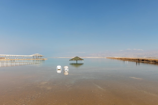 Luifel van de zon en twee stoelen in het water van de dode zee in Israël