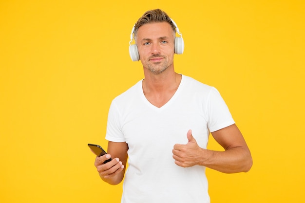 Luister goed liedje. guy moderne gebruiker mobiele applicatie. favoriete muziek afspeellijst. muziek abonnement. volwassen man luistert muziek moderne koptelefoon en smartphone. luisterconcept. beste muziek-apps.