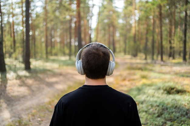 Luisteren naar muziek in de natuur met een koptelefoon, balans en harmonie kijkend naar het bos