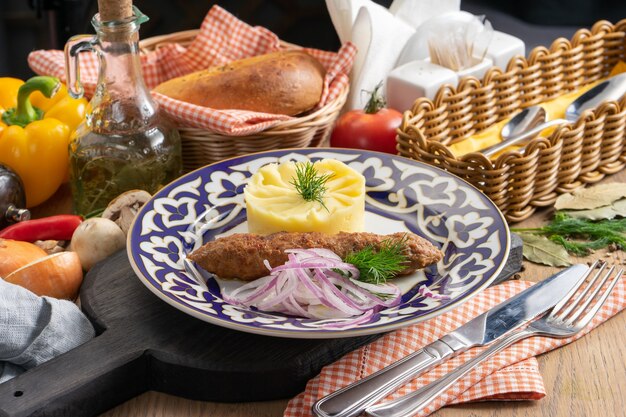 Lula kebab met aardappelpuree, uien en dille in een bord met een traditionele oezbeeks