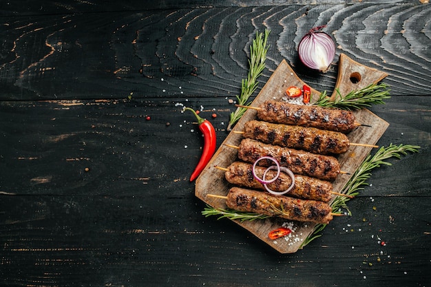 Люля кебаб традиционное кавказское блюдо На черном фоне бетона на разделочной доске с кетчупом, специями и помидорами копировать пространство выше