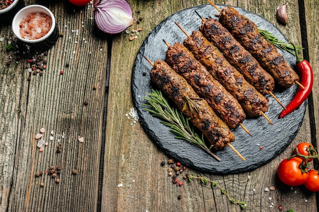 Lula kebab traditioneel Kaukasisch gerecht Op de zwarte achtergrond van het beton op een snijplank met ketchupkruiden en tomaten kopie ruimte erboven