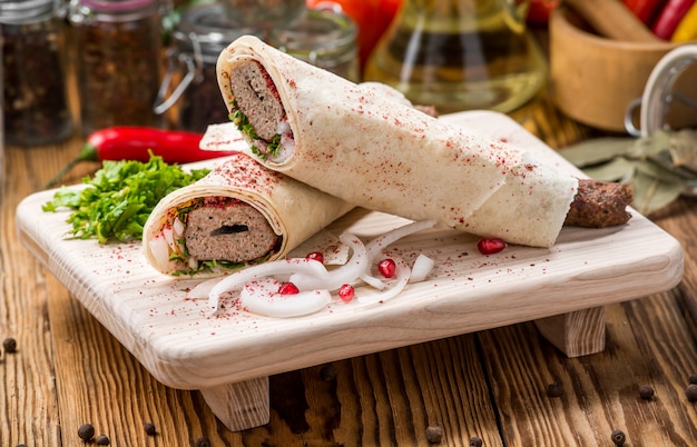 Lula kebab with herbs on a wooden surface