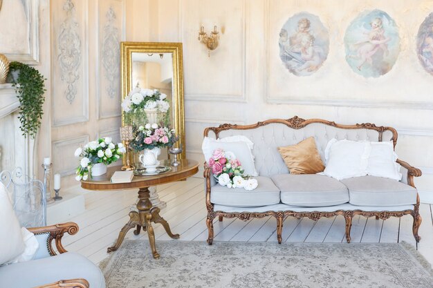 Роскошный интерьер богатой гостиной в бежевых пастельных тонах с антикварной дорогой мебелью в стиле барокко. стены украшены лепниной и фресками
