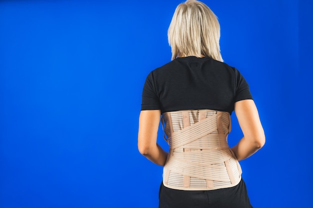 Фото Поясная скобка на человеческом теле изолирована на синем фоне травмы спины спины ортопедическая скобка