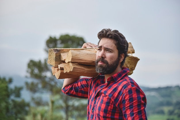 lumberjack bearded man carrying a log of wood