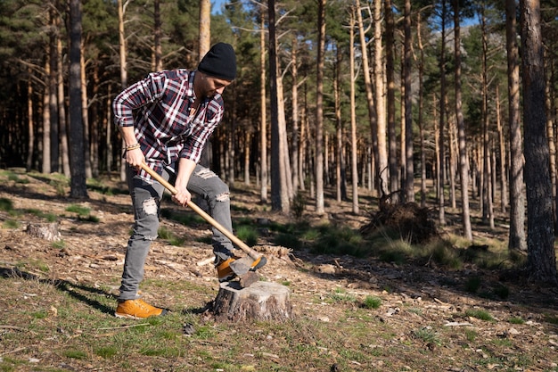 Uomo del boscaiolo che taglia la legna con l'ascia nella foresta