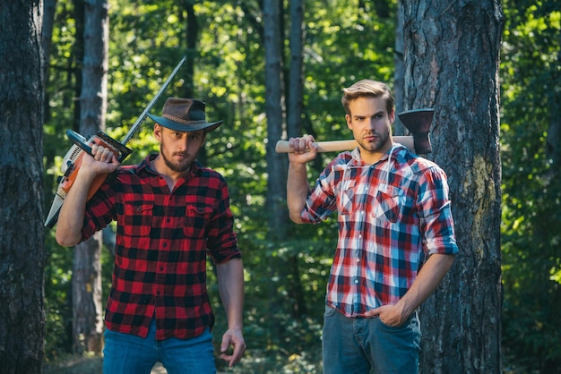 Photo lumberjack man in red checkered shirt with axe on wooden forest background forest workers