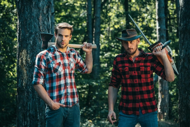 Lumberjack man in red checkered shirt with axe on wooden forest background forest workers