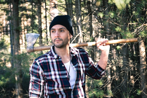 Lumberjack man with his ax on his shoulder in the forest