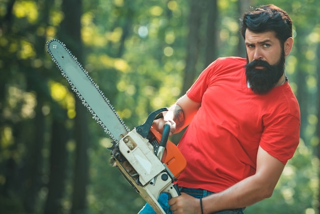 Lumberjack on serious face carries chainsaw. Agriculture and forestry theme. Lumberjack with