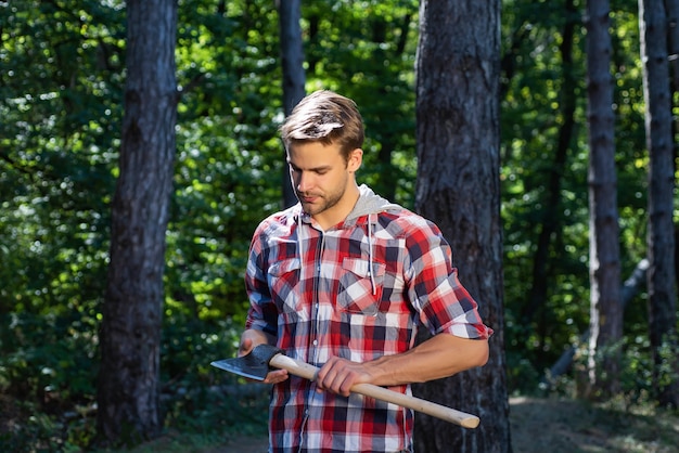 Lumberjack standing with axe on forest background. Deforestation is a major cause of land