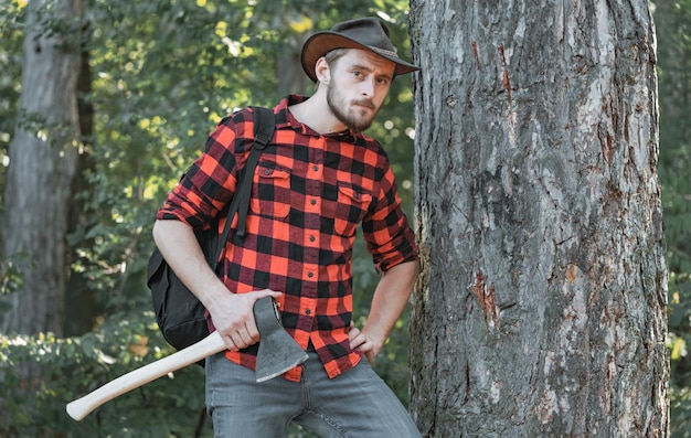 Foto boscaiolo con l'ascia nelle sue mani il boscaiolo che lavora in una foresta che riposa dopo il duro lavoro di woodcutte