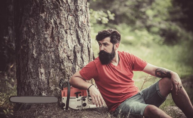 Lumberjack with chainsaw on forest background Lumberjack with chainsaw in his hands The Lumberjack w