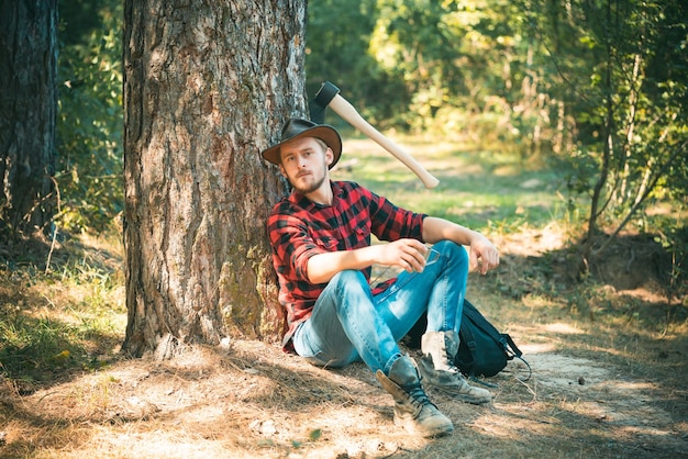 The lumberjack working in a forest handsome woodworkers lumberjack plaid shirt holding the axe on gr...