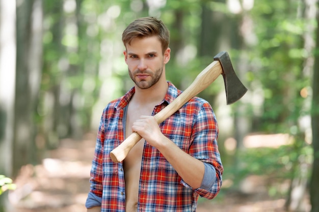 Lumbersexual man in houthakker shirt met bijl op schouder bos achtergrond