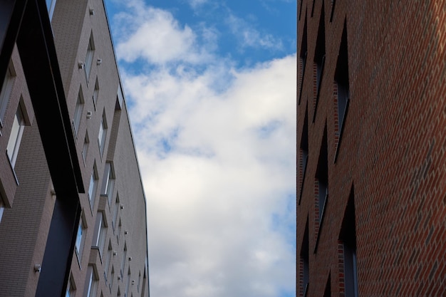 The lumen of the blue sky with clouds between walls of buildings