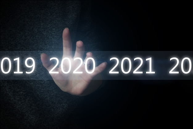 Фото Светящиеся числа 2020 года и сеть над рукой на черном фоне. новая технология 2020 года