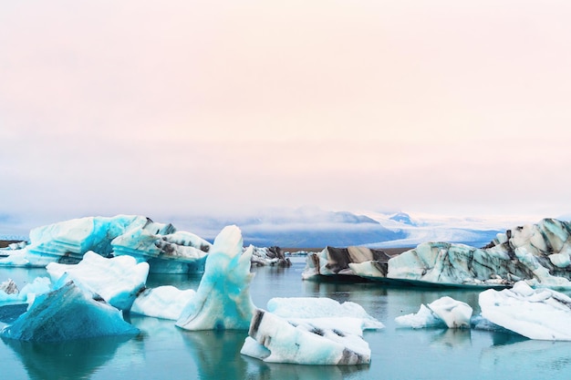 Luminous blue icebergs  floating in Jokulsarlon glacial lagoon with background of glacier mountain. South Iceland, VatnajÃ¶kull National Park. Copy space background. Place for text.