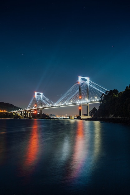 A luminous bridge reflecting in the water at night