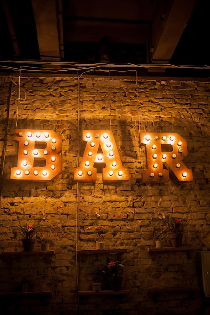 Luminous letters BAR Volumetric letters BAR from rusty metal on a brick wall