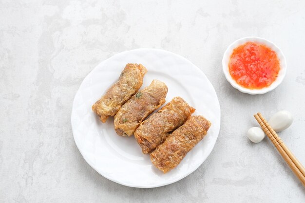 Lumpia Kulit Tahu, блинчики с начинкой из куриных креветок, завернутые в кожуру из тофу. Подается с соусом.