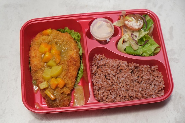 lunch box of healthy food bento with brown rice, chicken katsu with curry, salad lettuce, mayonnaise