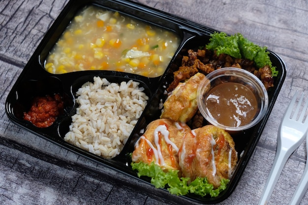 Lunch box of healthy food bento with brown rice, scrambled egg,\
corn soup, tempeh tofu. diet menu.